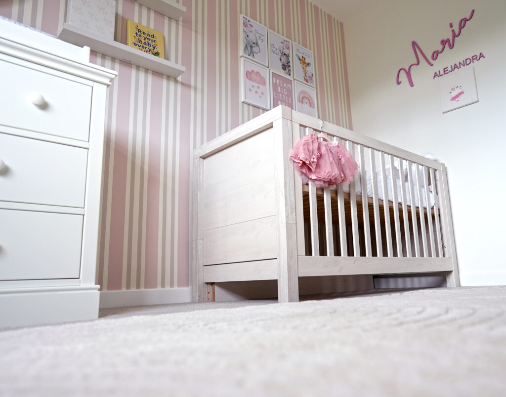 Pink girls nursery with pink tutu on cotbed_pink striped wallpaper