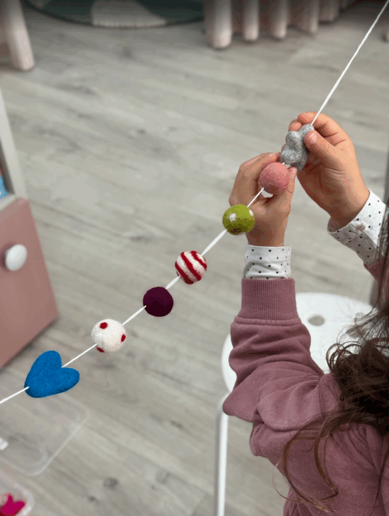 Child making a felt ball garland at MK Kids Interiors
